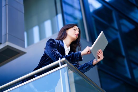 Business woman wearing blue suit using digital tablet in an office building. Lifestyle concept.