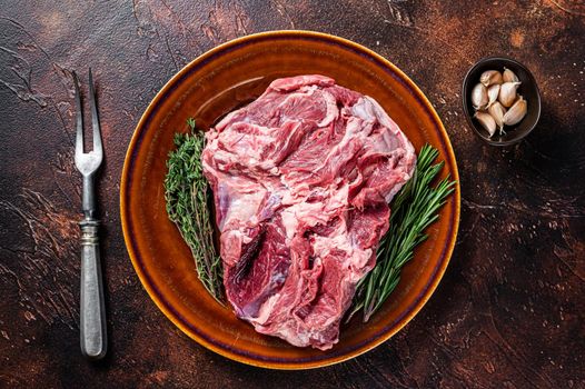 Raw Boneless Lamb leg meat in rustic plate with thyme. Dark background. Top view.