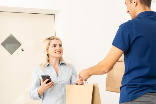 woman receiving boxes from postman at the door in home delivery concept. Woman received the parcel from the postman at home. Postman giving cardboard box to young woman.