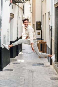 Happy man jumping in the street. Attractive Guy wearing casual clothes in urban background.