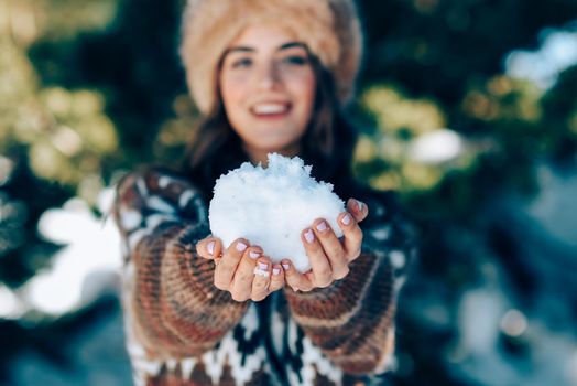 Young woman enjoying the snowy mountains in winter, in Sierra Nevada, Granada, Spain. Female wearing winter clothes playing with snow.