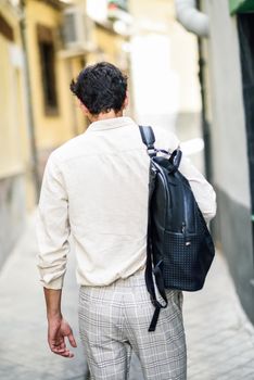 Young man sightseeing enjoying the streets of Granada, Spain. Male traveler carrying backpack in urban background.