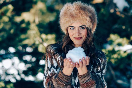 Young woman enjoying the snowy mountains in winter, in Sierra Nevada, Granada, Spain. Female wearing winter clothes playing with snow.