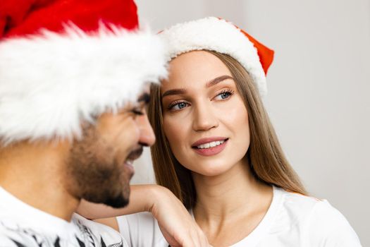 Cheerful attractive happy couple in Santa hats, close up portrait