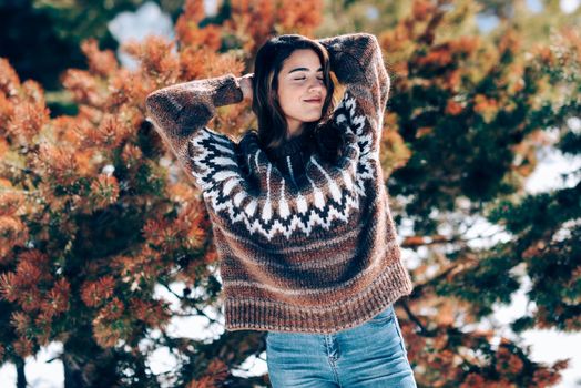 Young woman enjoying the snowy mountains in winter, in Sierra Nevada, Granada, Spain. Female wearing winter clothes.