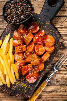 Currywurst Sausages street food served French fries on a wooden board. wooden background. Top view.