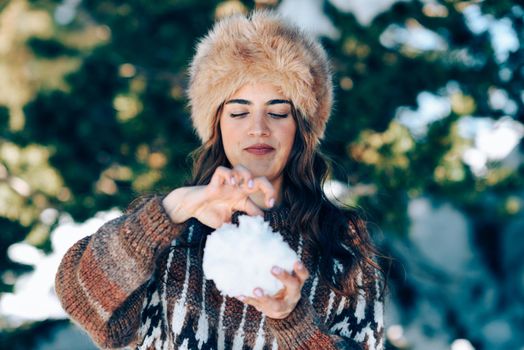 Young woman enjoying the snowy mountains in winter, in Sierra Nevada, Granada, Spain. Female wearing winter clothes playing with snow.