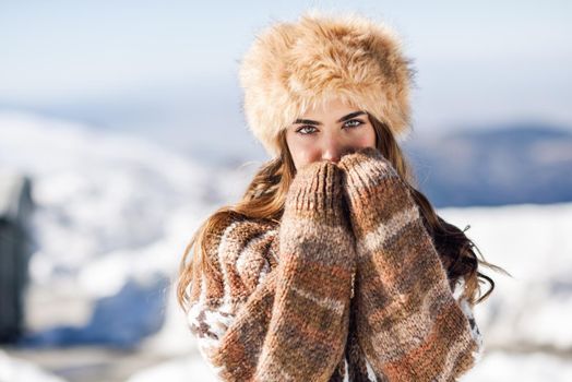 Beautiful woman enjoying the snowy mountains in winter, in Sierra Nevada, Granada, Spain. Female wearing winter clothes.