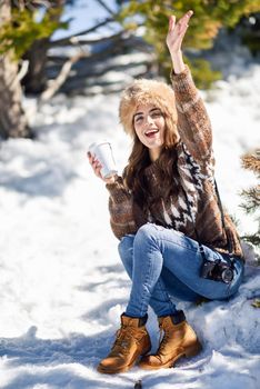 Female wearing winter clothes drinking hot coffee. Young woman enjoying the snowy mountains in winter, in Sierra Nevada, Granada, Spain.
