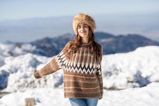 Young woman enjoying the snowy mountains in winter, in Sierra Nevada, Granada, Spain. Female wearing winter clothes.