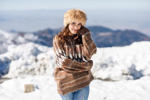 Young woman enjoying the snowy mountains in winter, in Sierra Nevada, Granada, Spain. Female wearing winter clothes.