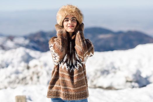 Young woman enjoying the snowy mountains in winter, in Sierra Nevada, Granada, Spain. Female wearing winter clothes.