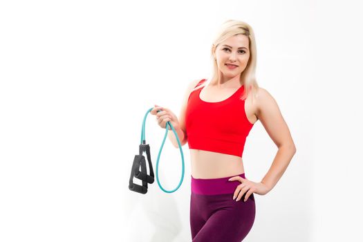 Close up portrait of a confident young fitness woman doing exercises with hand expander isolated over gray background