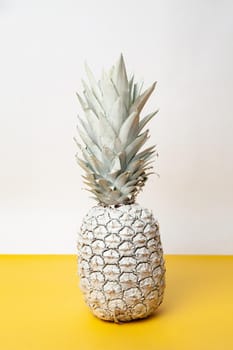 White whole fresh pineapple placed on table in modern studio on white and yellow background