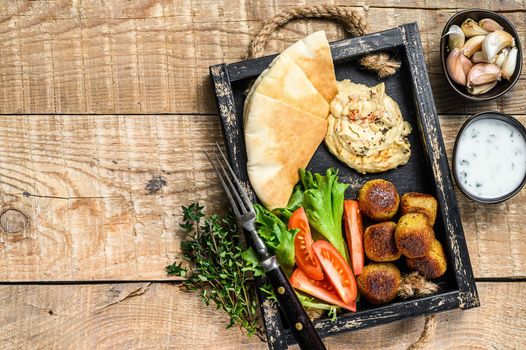 Arabic cuisine Hummus chickpea, falafel, pita bread and fresh vegetables. wooden background. Top view. Copy space.