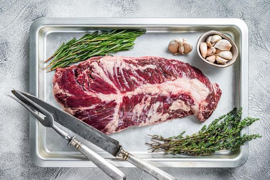 Raw hanger or onglet beef meat steak in steel tray with herbs. White background. Top View.