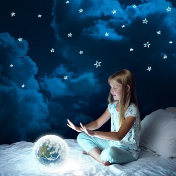 Cute girl sitting in bed and looking at Earth planet. Elements of this image are furnished by NASA