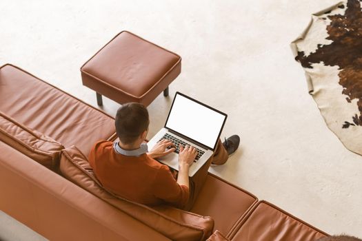 Man using notebook with blank screen in living room.