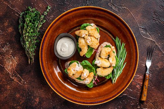 Sandwichs with Fried Shrimps, Prawns, spinach and chard salad on a rustic plate. Dark background. Top view.