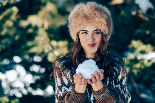 Young woman enjoying the snowy mountains in winter, in Sierra Nevada, Granada, Spain. Female wearing winter clothes playing with snow.