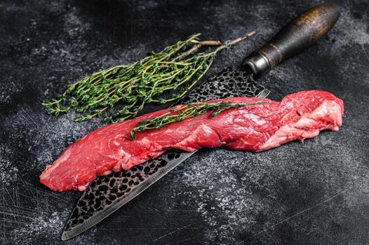 Raw skirt machete beef steak on a meat cleaver. Black background. Top view.