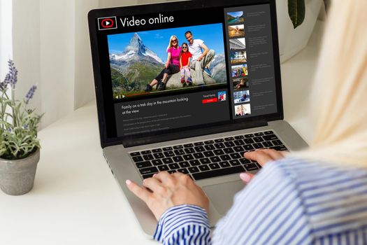 Woman watching videos online on laptop.