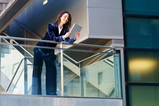 Business woman wearing blue suit using digital tablet in an office building. Lifestyle concept.