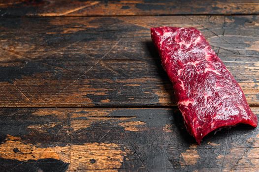 Raw machete or skirt beef steak. Dark wooden background. Top view. Copy space.