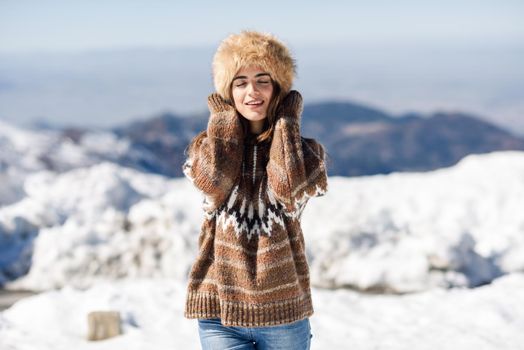 Young woman enjoying the snowy mountains in winter, in Sierra Nevada, Granada, Spain. Female wearing winter clothes.