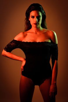 Young brunette woman in black lingerie with red and green lighting. Attractive girl, model of fashion with studio complementary colors.