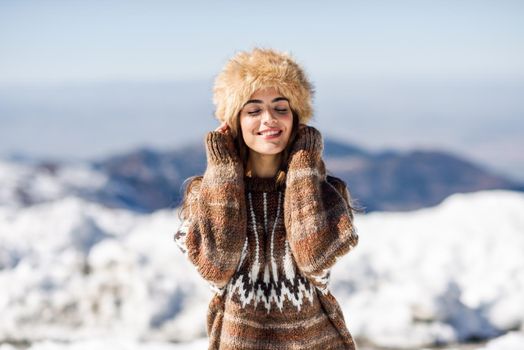 Beautiful woman enjoying the snowy mountains in winter, in Sierra Nevada, Granada, Spain. Female wearing winter clothes.