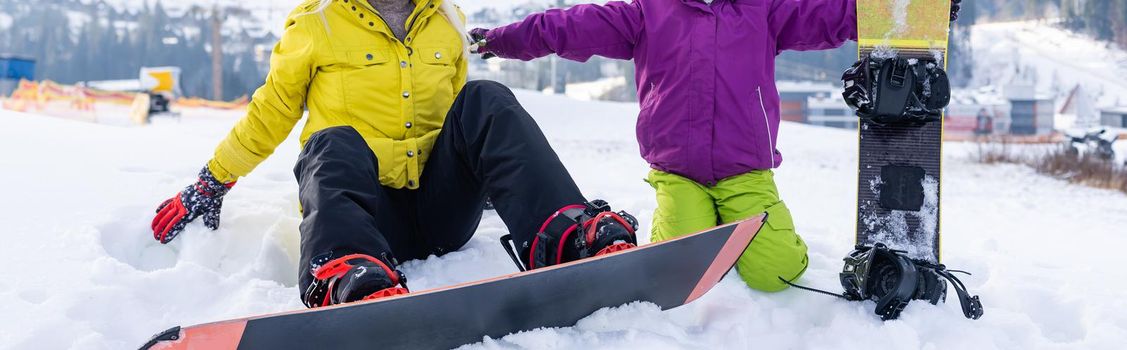 mother and daughter with snowboards at winter resort