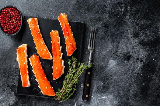 Crab legs Phalanx on a marble board with thyme. Black background. Top view. Copy space.