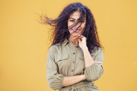 Young Arab Woman with curly hair in her face on urban yellow wall