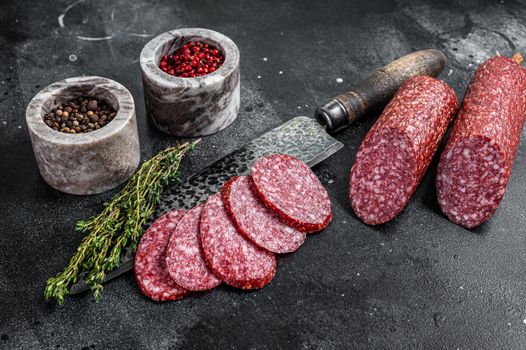 Traditional smoked salami cured sausage on kitchen table. Black background. Top view.