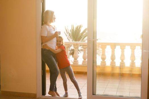 Woman near window facing the sunrise at morning