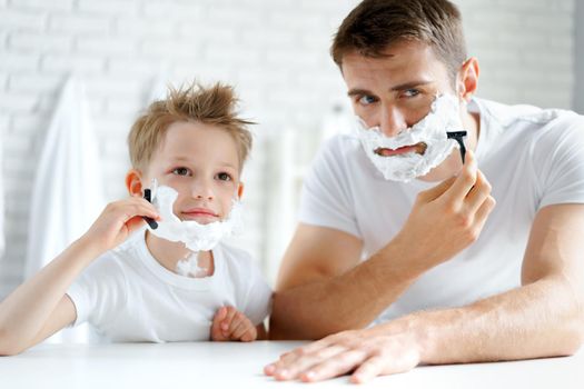 Father and his little son shaving together in bathroom