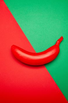 From above of unusual red whole unpeeled banana placed on two color background