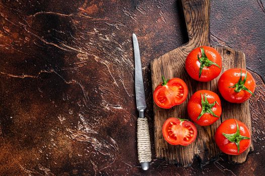 Cut Red cherry tomatoes on wooden cutting board. Dark background. Top view. Copy space.