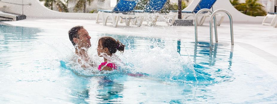 Father playing with his daughter in swimming pool.