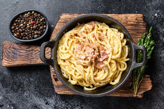 Pasta Carbonara with bacon and parmesan in a pan. Black background. top view.