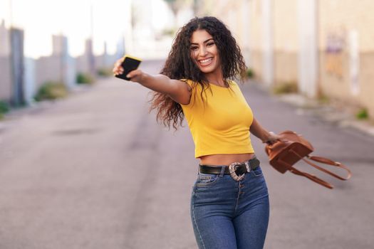 Happy Arab woman wearing casual clothes with open arms in the street.