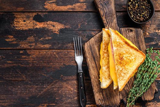 Fried ham and melted cheese sandwich. Dark wooden background. Top view. Copy space.