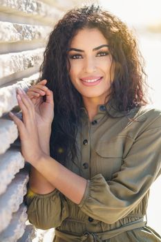 Smiling Arab Woman with curly hair in urban background