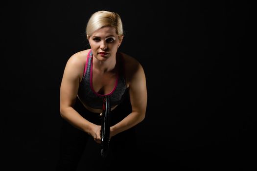 Young female tennis player posing with racket on black background