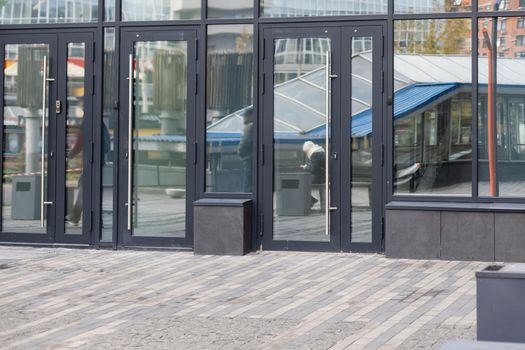 The front door of a office block, reflecting buildings in the glass.