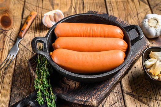 Sausages bratwurst from pork meat in a pan. wooden background. top view.