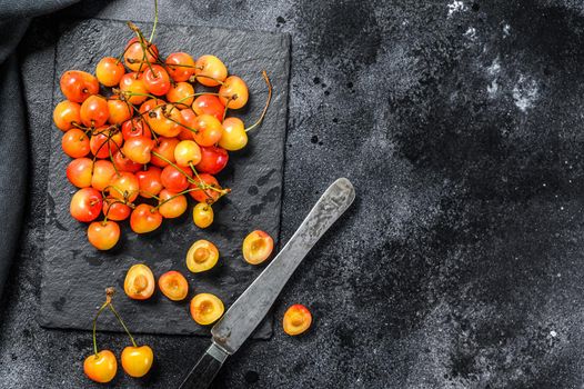 Mix of yellow and red ripe cherries. Black background. Top view. Copy space.