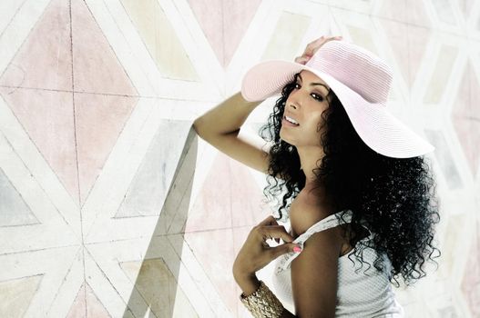 Portrait of a young black woman, model of fashion wearing dress and sun hat, with afro hairstyle in urban background