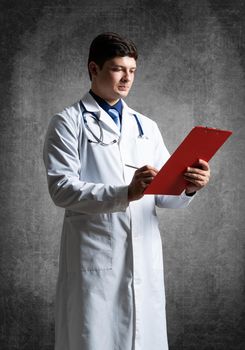 Doctor with tablet for documents, scans documents against the background of the wall